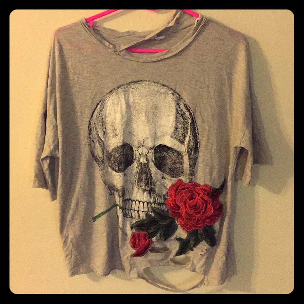 A ripped shirt with a skull print and rose patch.